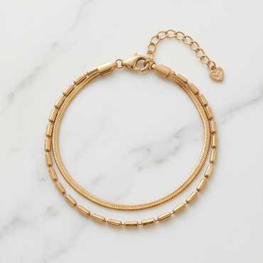Gold double layer bracelet with snake chain and beaded chain on white marble surface
