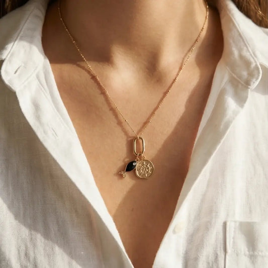 gold charm necklace with black fish and helm pendant worn on woman, 18k gold plated layering necklace elegant everyday jewelry