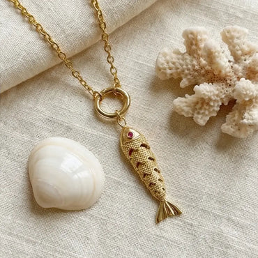 Gold fish charm necklace on chain with seashell and coral aesthetic beach inspired jewelry flat lay