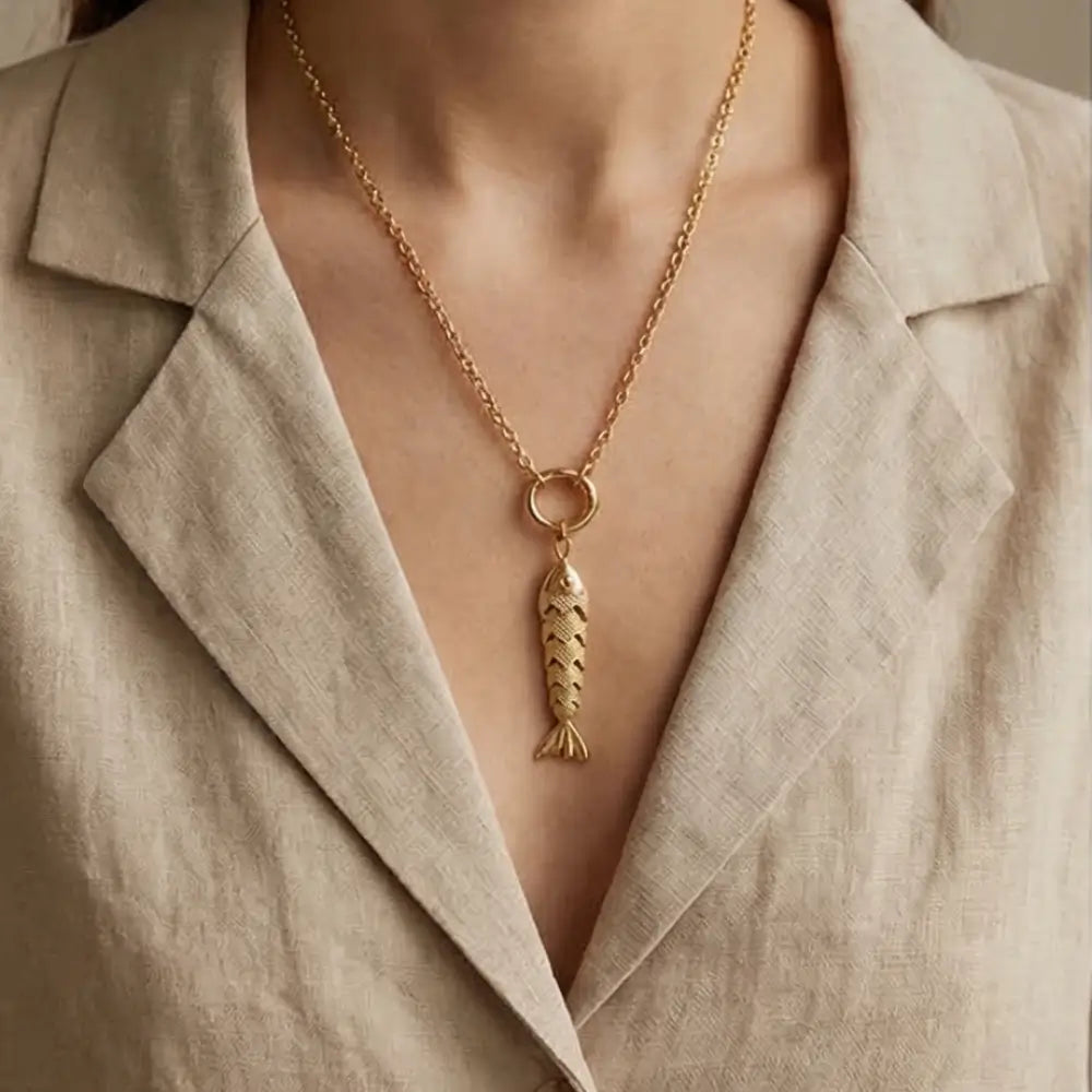 Gold fish pendant necklace worn by woman with minimalist outfit luxury jewelry style
