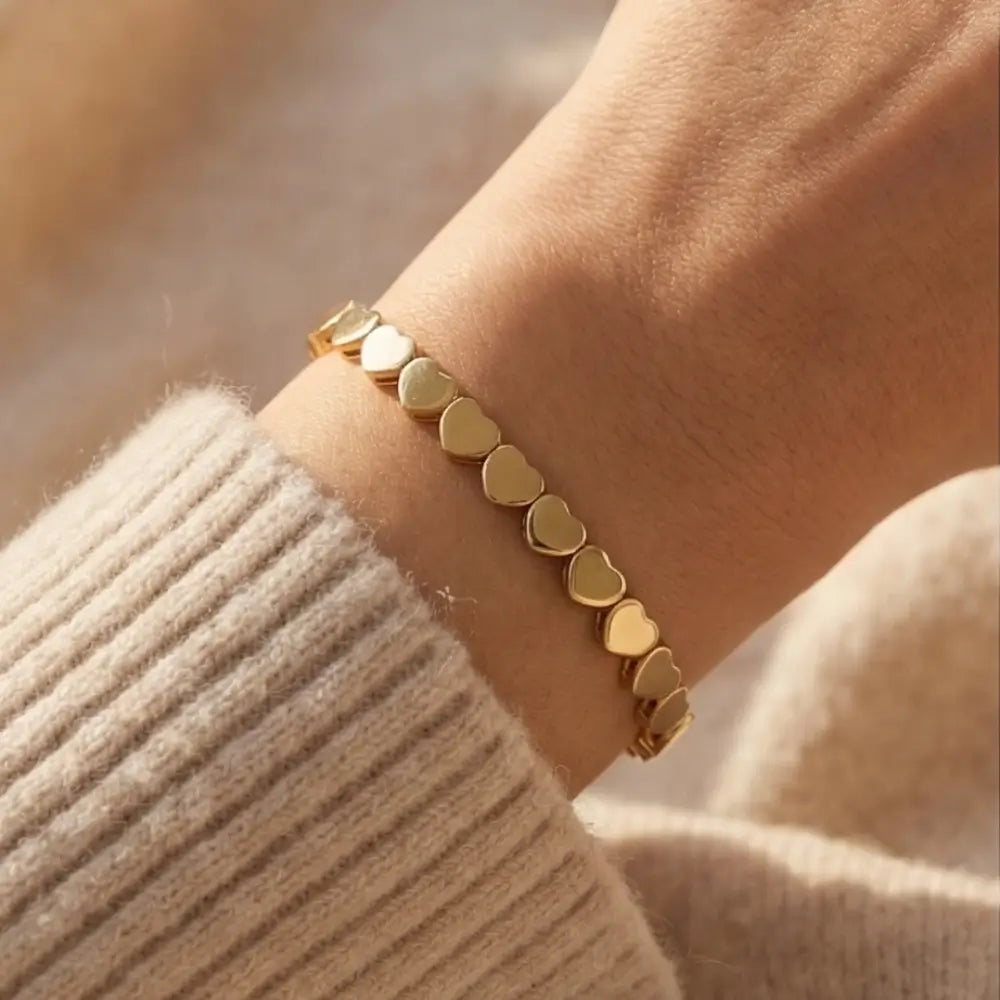 Gold heart-shaped bracelet on a wrist with a blurred background