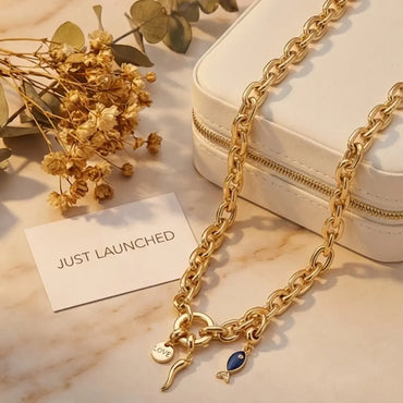 Lucky charms gold chain necklace with love coin charm, horn charm and blue enamel fish pendant on chunky gold chain.
