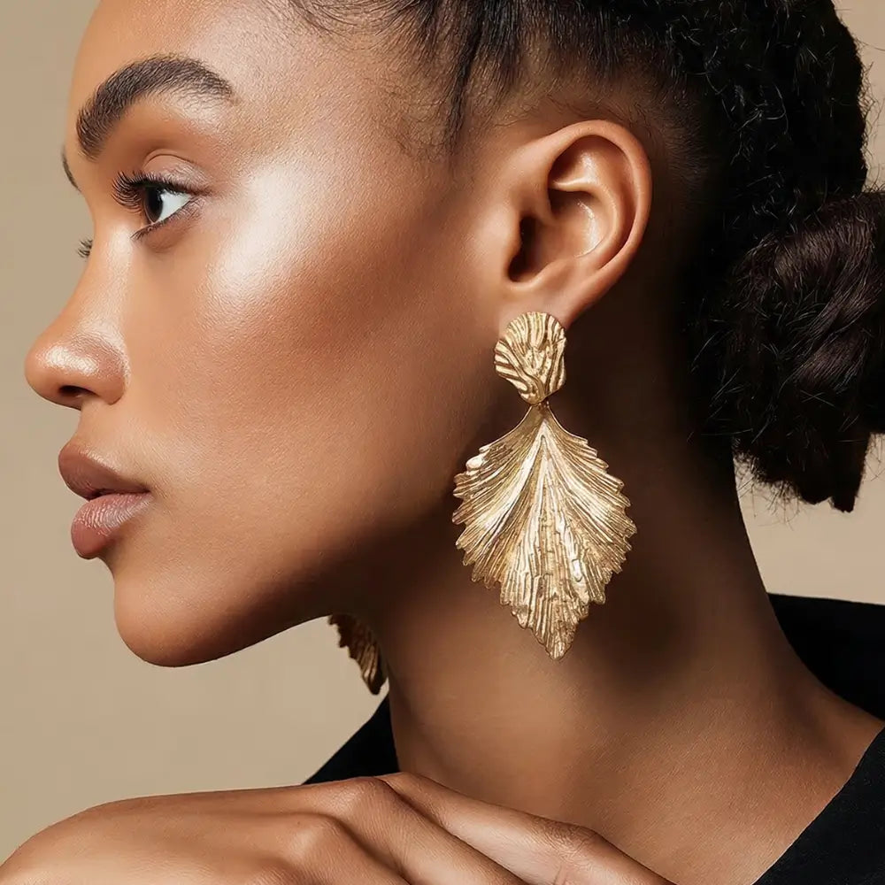 Close-up of a woman wearing gold earrings against a neutral background