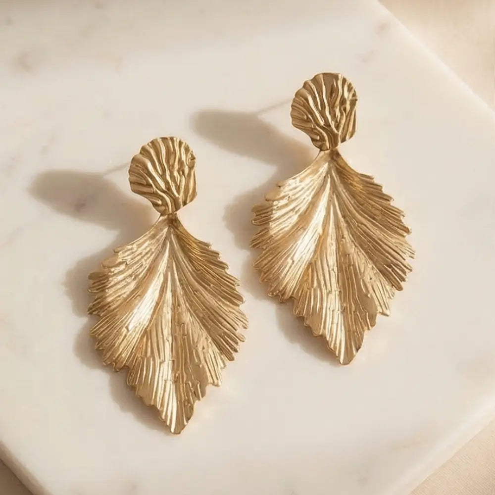 gold leaf statement earrings textured gold drop earrings luxury handmade jewelry flat lay neutral background