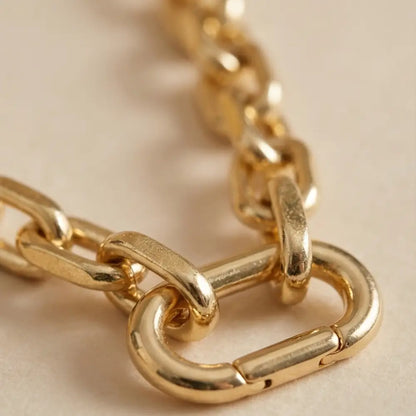 Close-up of gold paperclip chain necklace clasp detail with polished finish