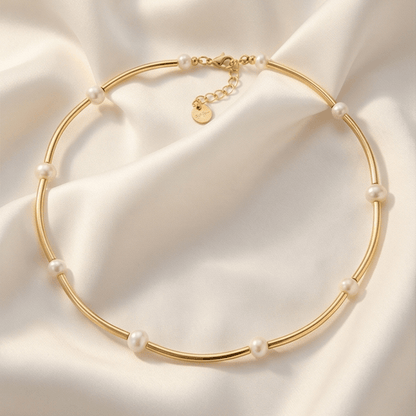Gold necklace with pearls on a soft beige fabric background