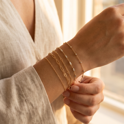 Gold permanent bracelet stack with delicate chains custom-fitted for a minimal luxury look.