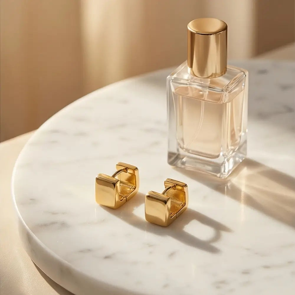 minimal gold rectangular huggie earrings on marble tray with perfume aesthetic