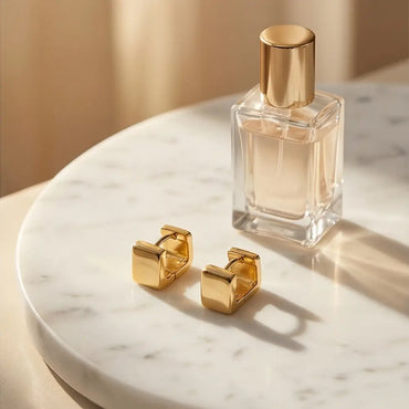 minimal gold rectangular huggie earrings on marble tray with perfume aesthetic