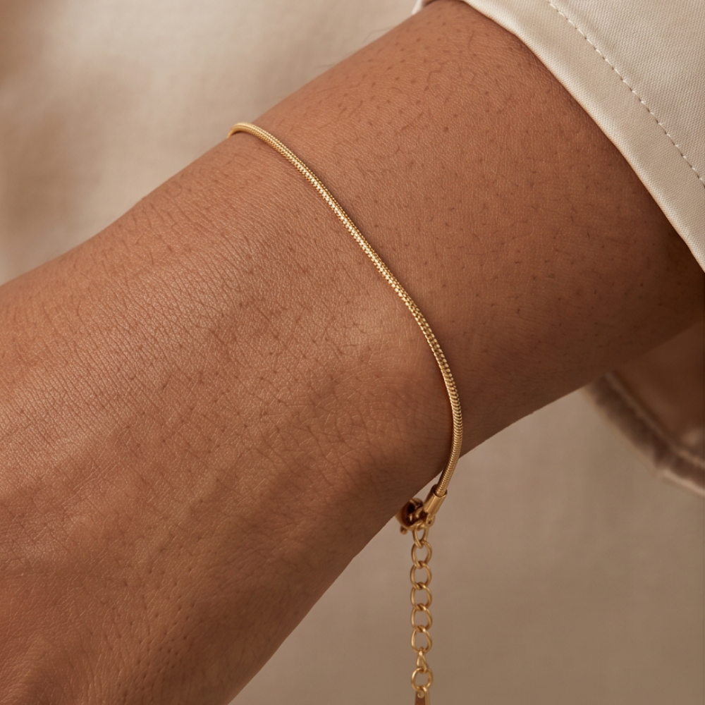 Gold anklet on a person's ankle against a neutral background