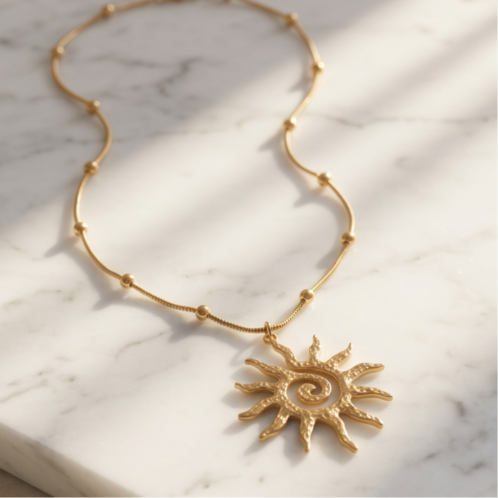 Gold sun pendant necklace displayed on white marble surface with textured celestial charm