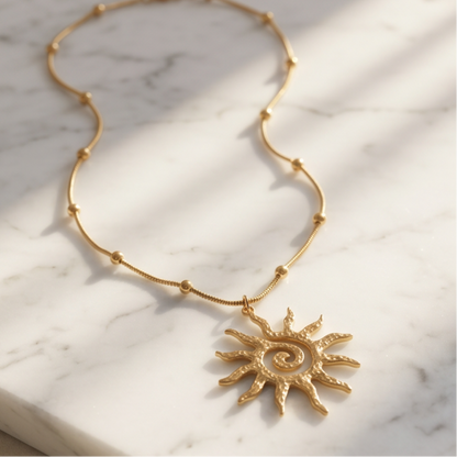 Gold sun pendant necklace displayed on white marble surface with textured celestial charm