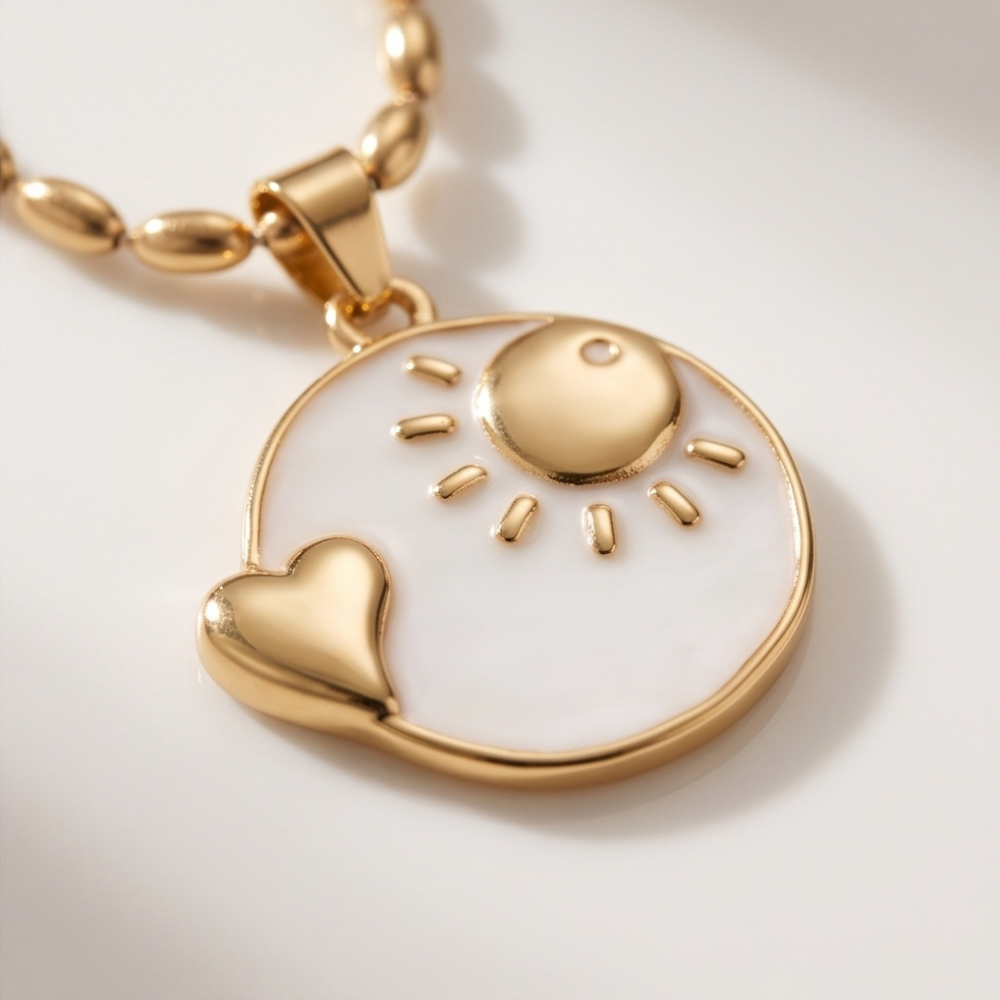 Close-up of gold and white enamel sun pendant necklace with heart detail