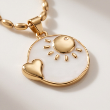 Close-up of gold and white enamel sun pendant necklace with heart detail