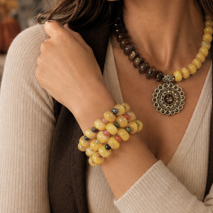 Close-up of woman wearing Golden Earth brown and mustard acrylic bead necklace with antique gold-tone medallion