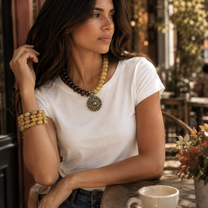 Woman wearing Golden Earth brown and mustard statement necklace with antique gold medallion in a fall lifestyle setting