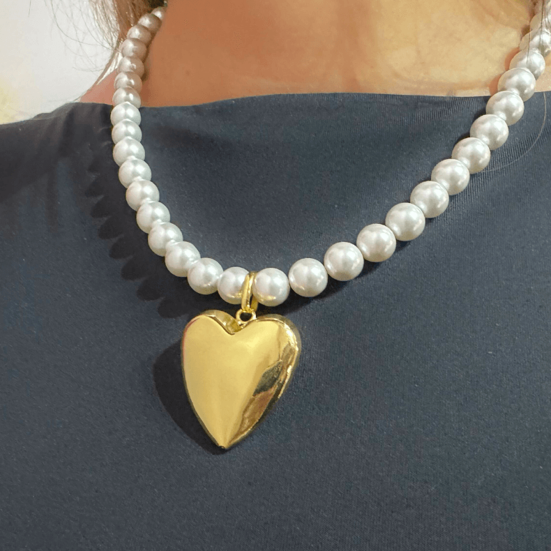 A timeless pearl necklace featuring a beautiful gold heart pendant. The necklace consists of high-quality pearls and an 18K gold-plated heart pendant. It includes an adjustable chain for a comfortable fit. The design is elegant and versatile, suitable for both professional and casual wear, ideal for business women aged 35-60.