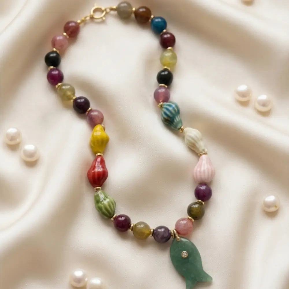 Handmade colorful gemstone necklace with fish pendant flat lay elegant jewelry