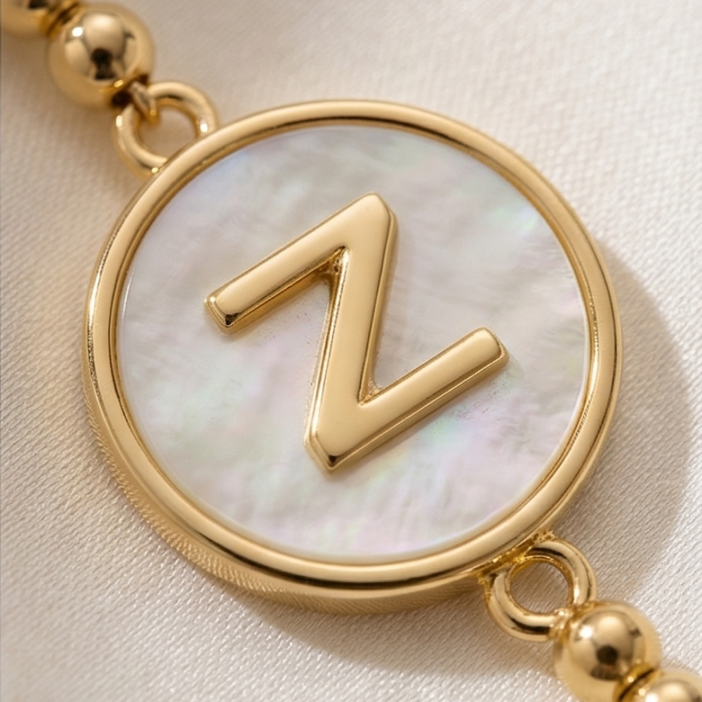 Gold bracelet with a circular charm featuring the letter 'Z' on a light background
