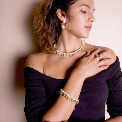 Woman wearing pearl charm necklace with gold dangle charms and matching bracelet, elegant statement jewelry Julie Saldivia