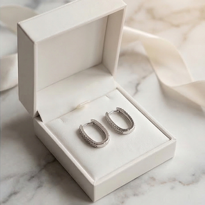Silver hoop earrings in an open jewelry box on a marble surface
