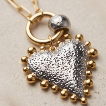 Close-up of Luna silver heart pendant with gold bead detailing
