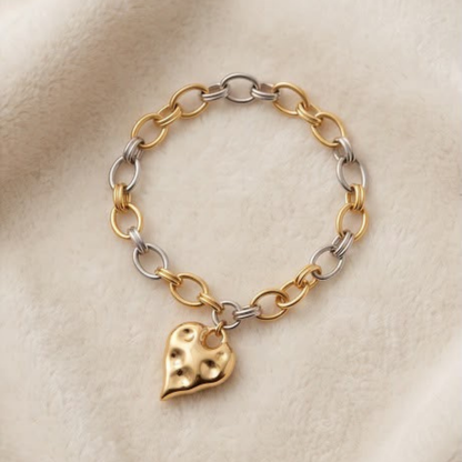 Flat lay of two-tone heart charm bracelet with gold and silver links from Julie Saldivia Modern Relics Collection