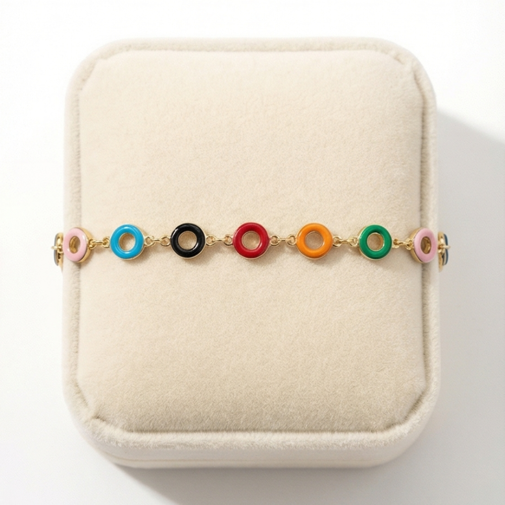 Colorful bracelet with gold chain on a beige cushion