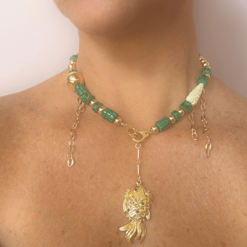 16-inch 18k gold-plated necklace featuring malachite stones and a unique fish charm with an emerald green rhinestone, designed to add a touch of sophistication and coastal charm to any outfit."