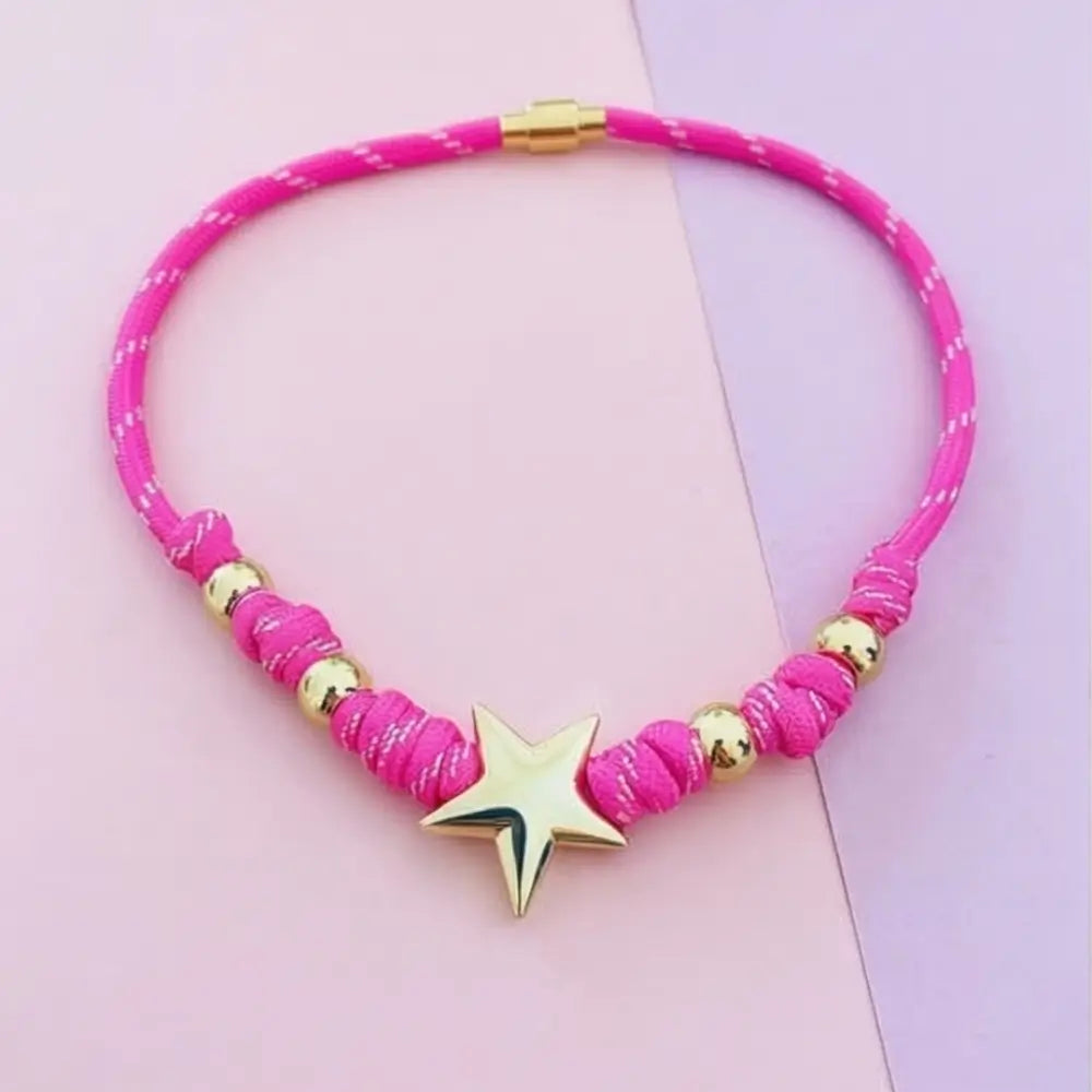 Pink necklace with gold accents and a star pendant on a pink background