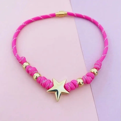 Pink necklace with gold accents and a star pendant on a pink background