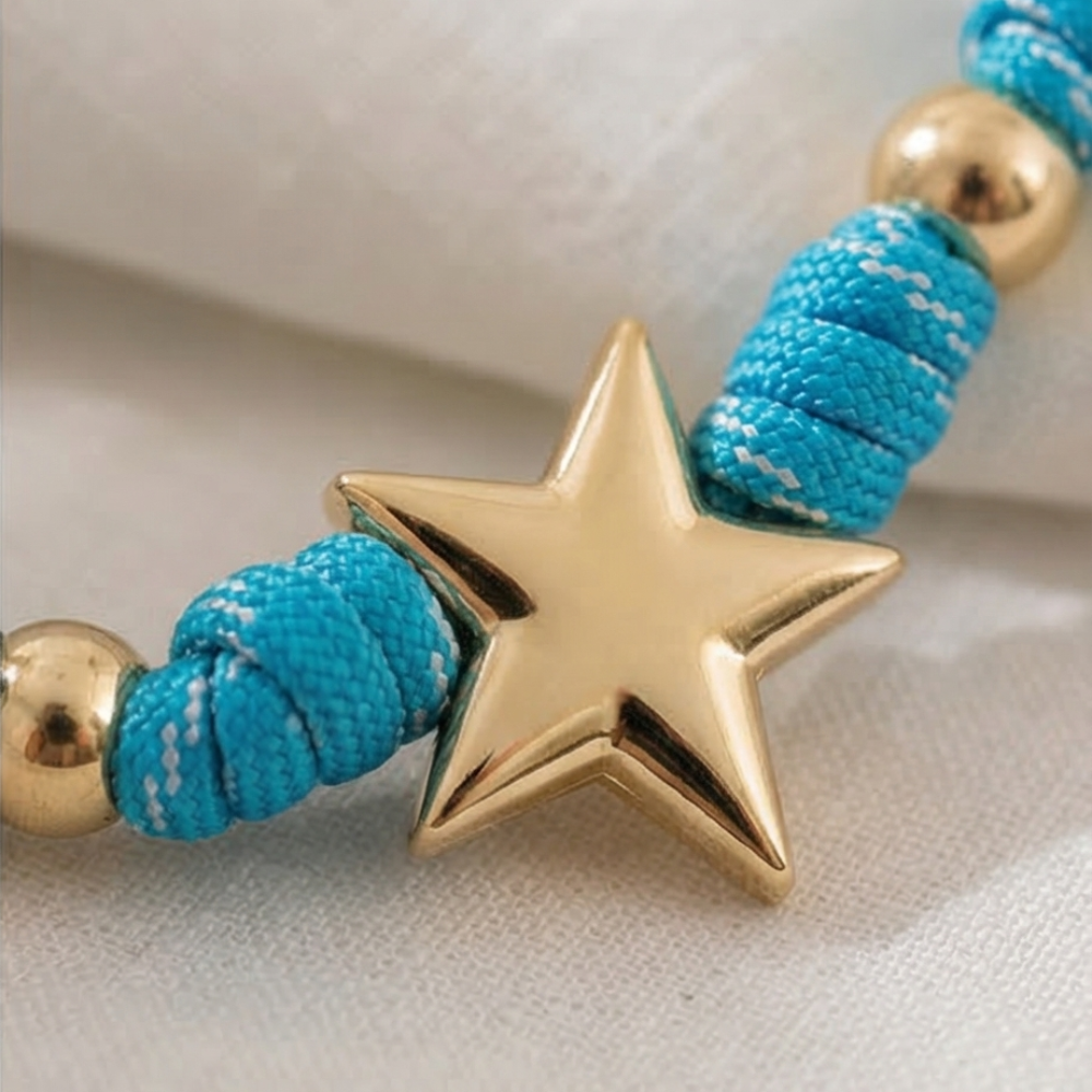 NECKLACE with turquoise cord and gold star charm on a light background