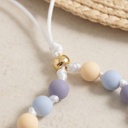 Necklace with pastel-colored beads on a beige surface
