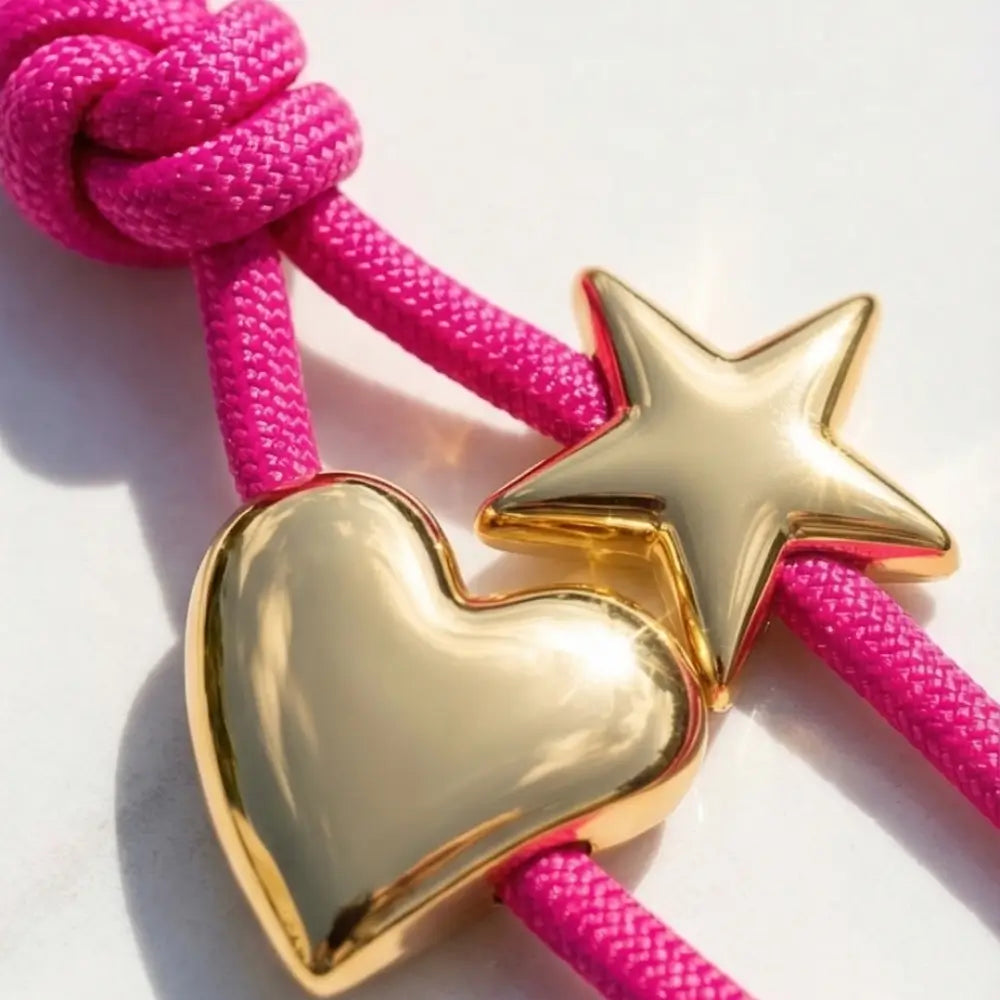 Gold heart and star charm on a pink rope against a white background