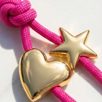 Gold heart and star charm on a pink rope against a white background
