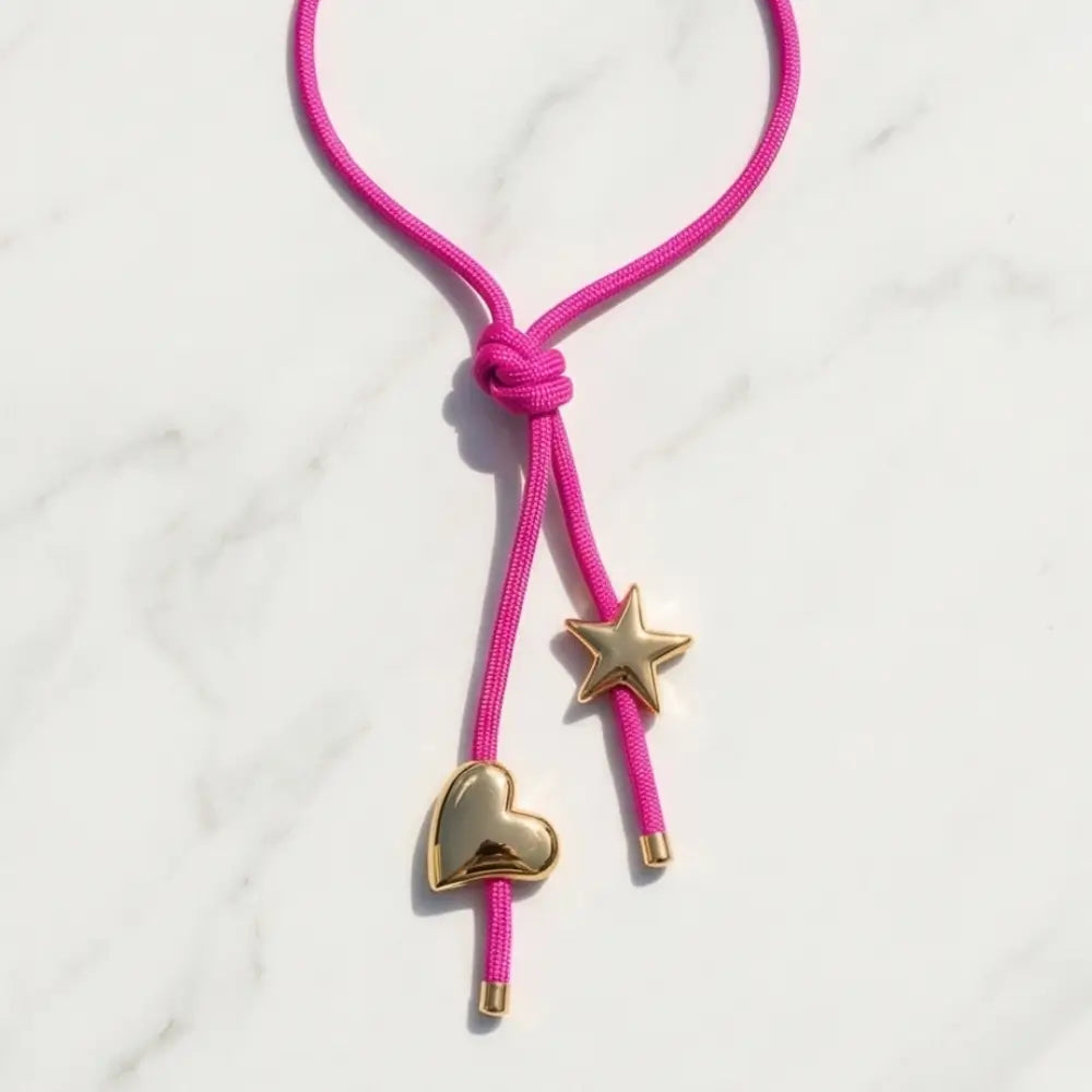 Pink cord with gold heart and star charms on a white background