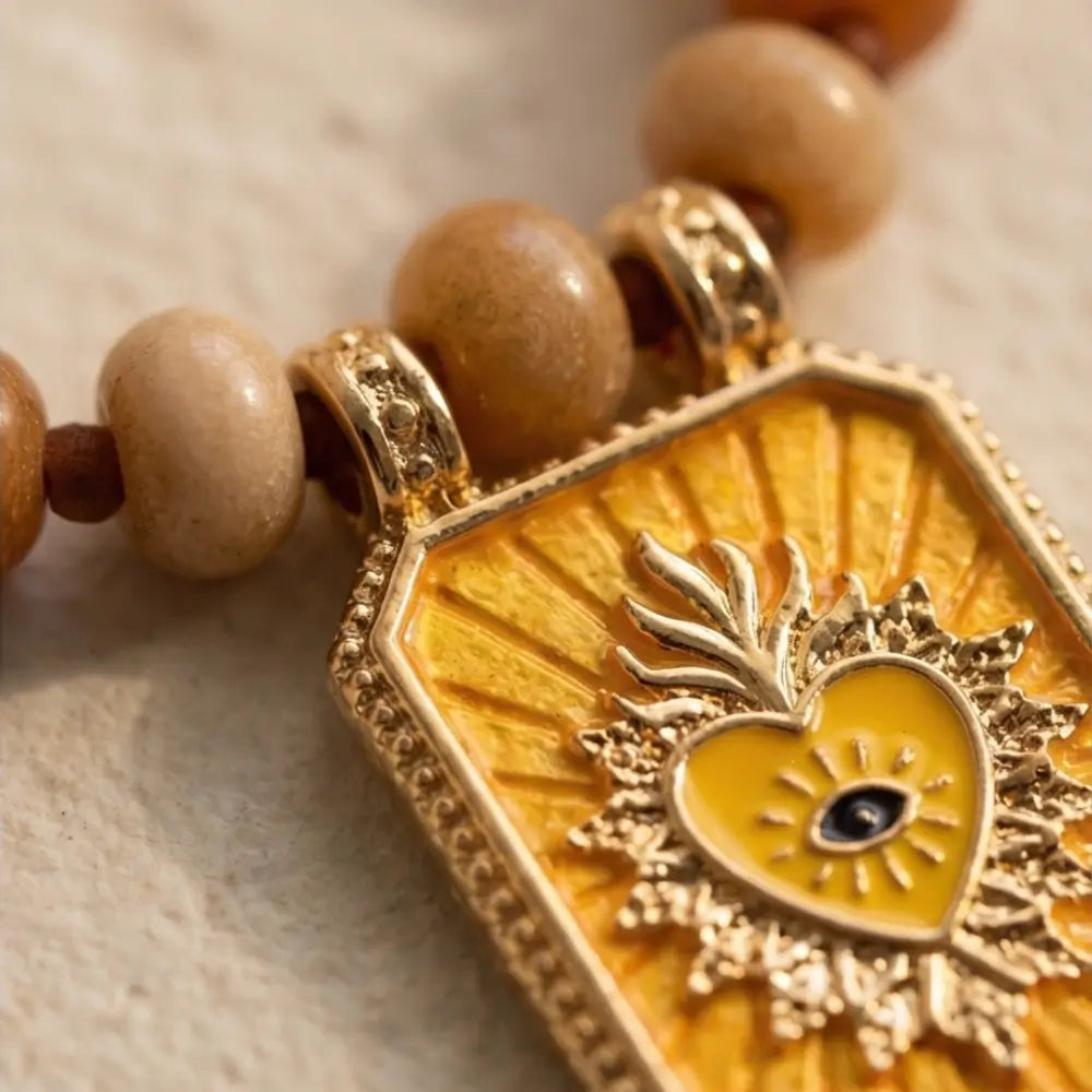 Close up sacred heart pendant with yellow enamel on beaded necklace handmade design