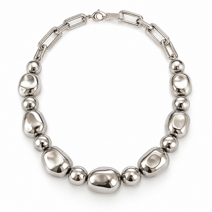 A polished silver-tone metal necklace featuring a combination of smooth oval beads and spherical beads connected by a paperclip chain, displayed on a clean white background.