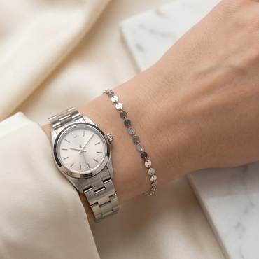Silver disc permanent bracelet styled with a watch for an elegant everyday jewelry look.