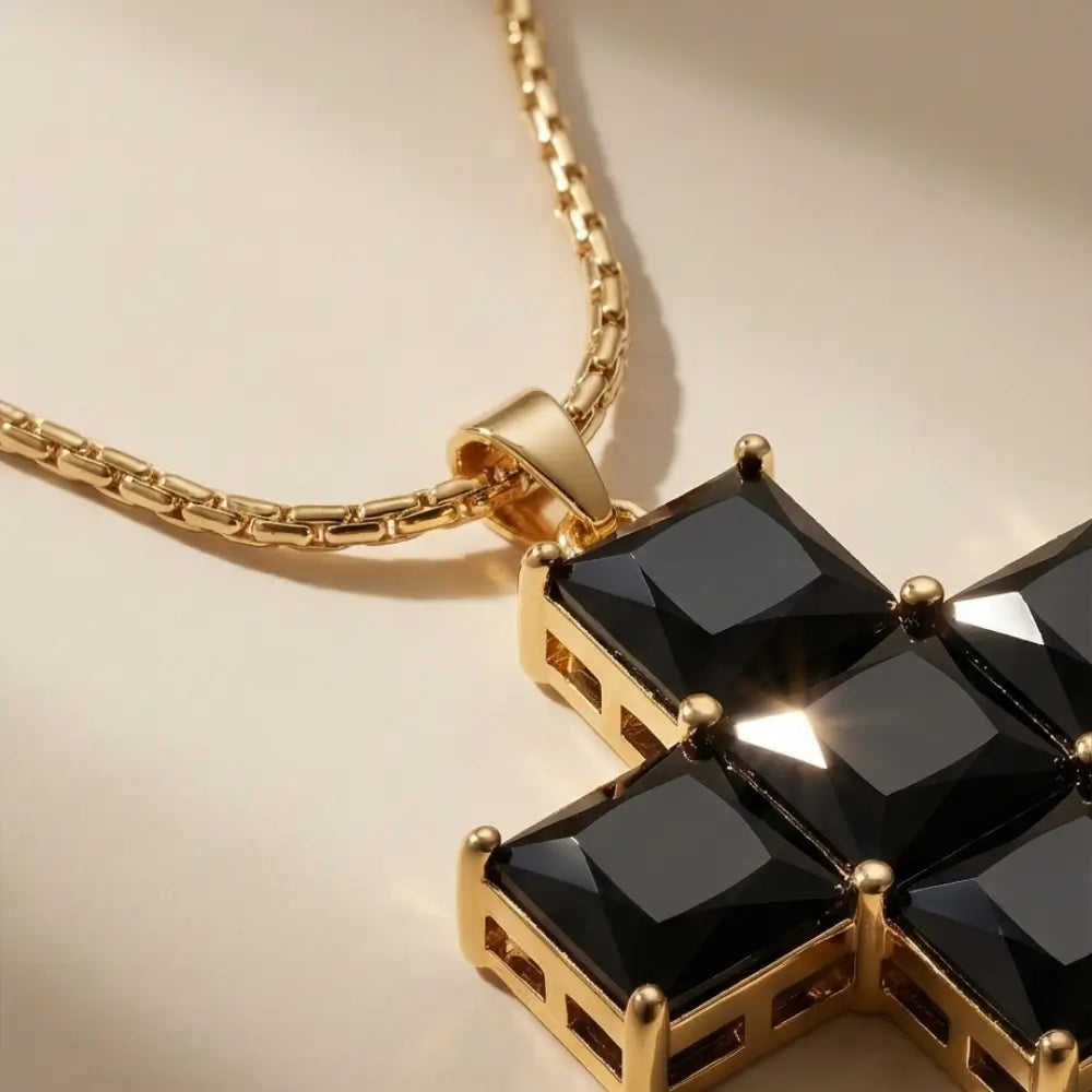 Gold necklace with a black gemstone pendant on a beige background