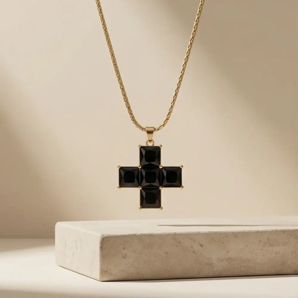 Gold necklace with a black cross pendant on a beige background