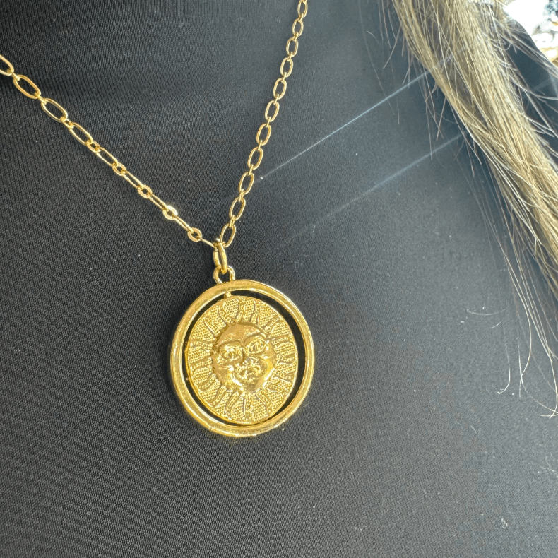 Close-up of a sterling gold 925 necklace with a reversible sun and moon charm.