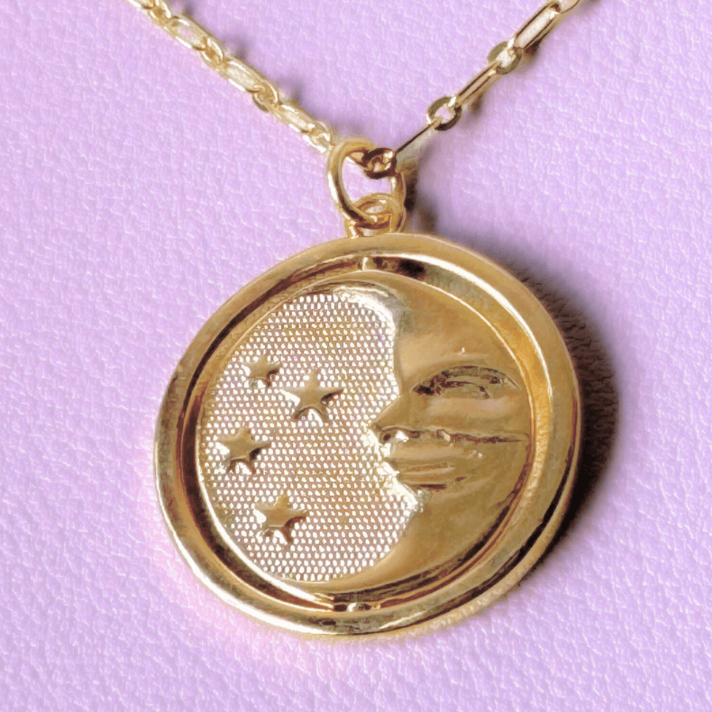 Close-up of a sterling gold 925 necklace with a reversible sun and moon charm.