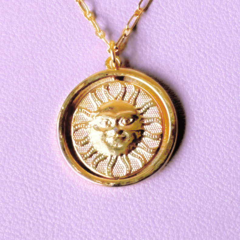 Close-up of a sterling gold 925 necklace with a reversible sun and moon charm.