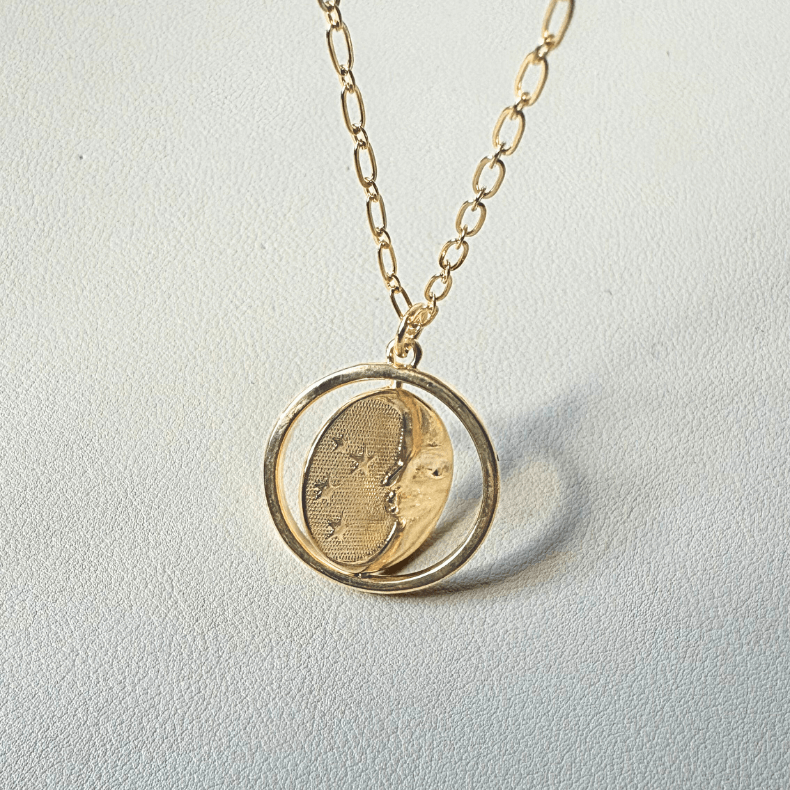 Close-up of a sterling gold 925 necklace with a reversible sun and moon charm.