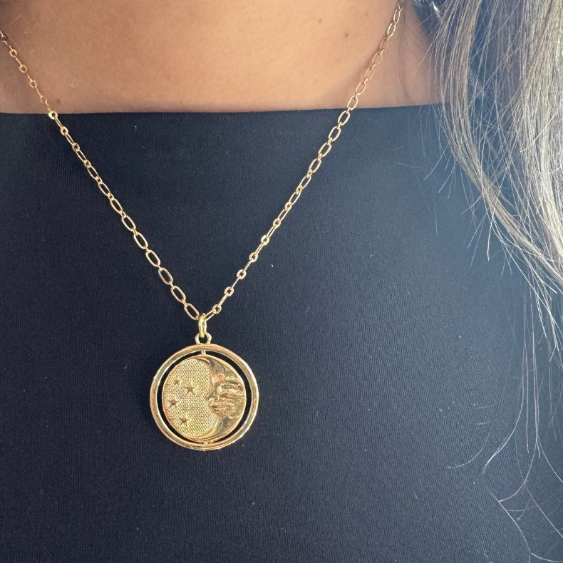 Close-up of a sterling gold 925 necklace with a reversible sun and moon charm.