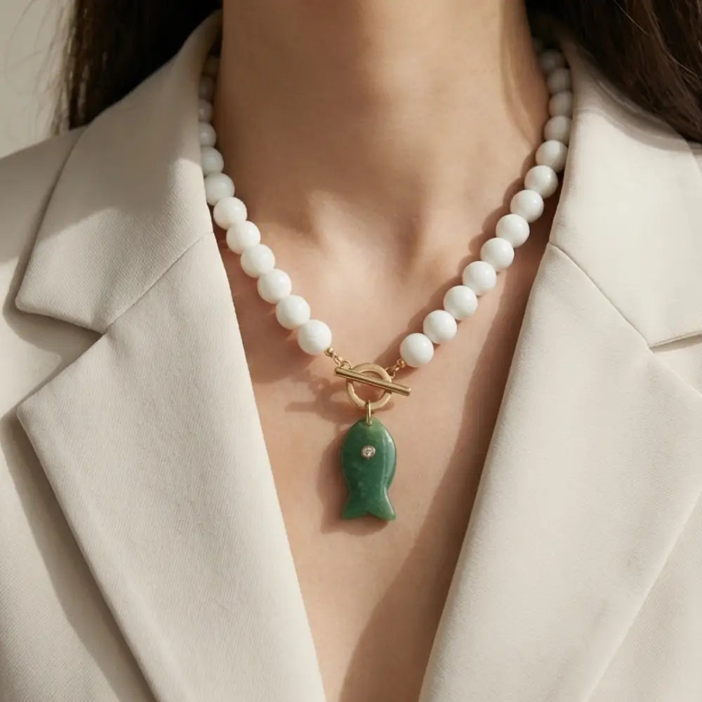 Woman wearing white beaded necklace with green fish pendant elegant statement jewelry